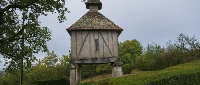 Ancien pigeonnier en pierre et bois dans un jardin arboré